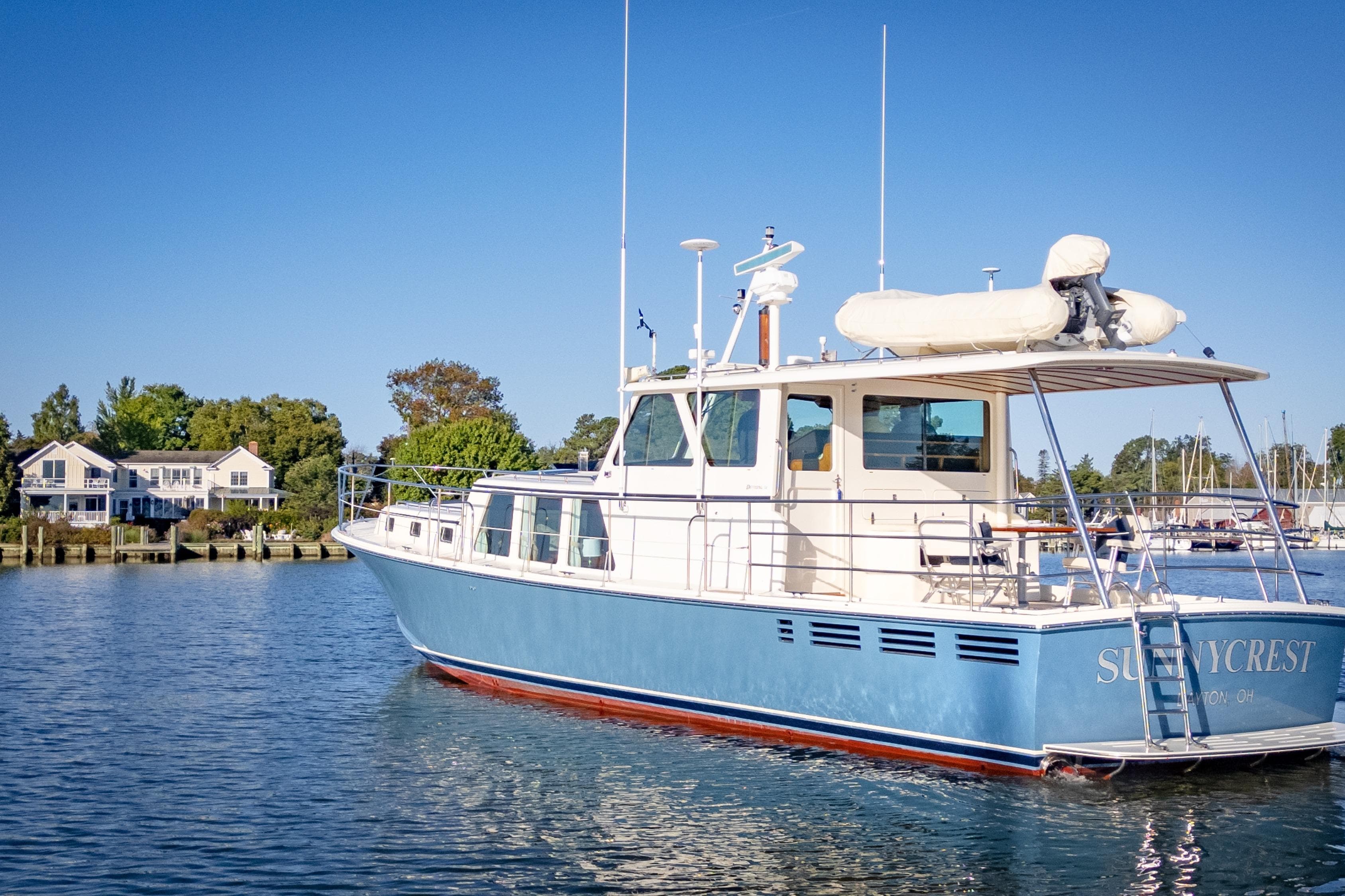 Luxury Dettling 51 yacht from 2001 on serene water, with houses in the background.