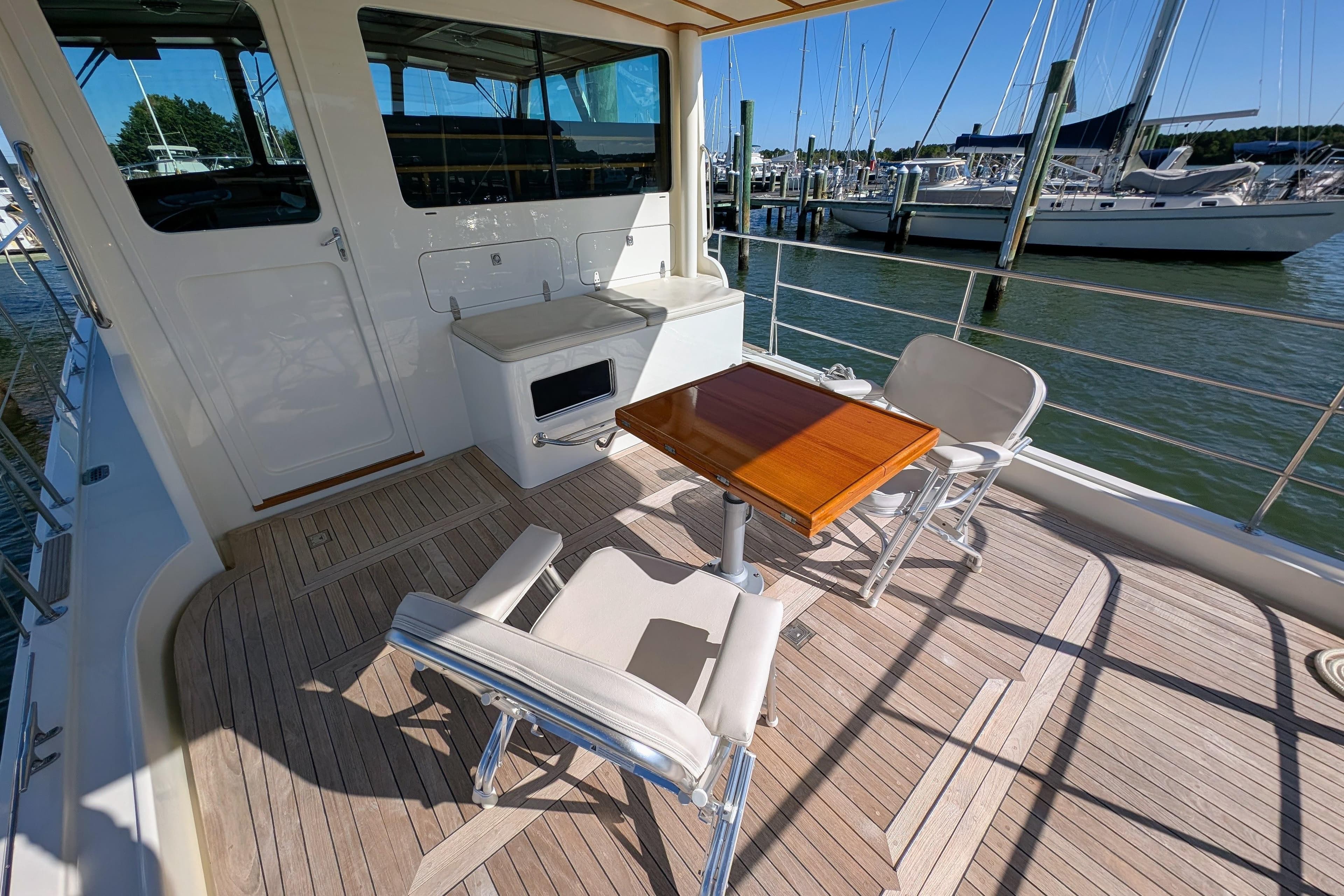 Outdoor seating area on 2001 Dettling 51 yacht with wooden deck and marina view.