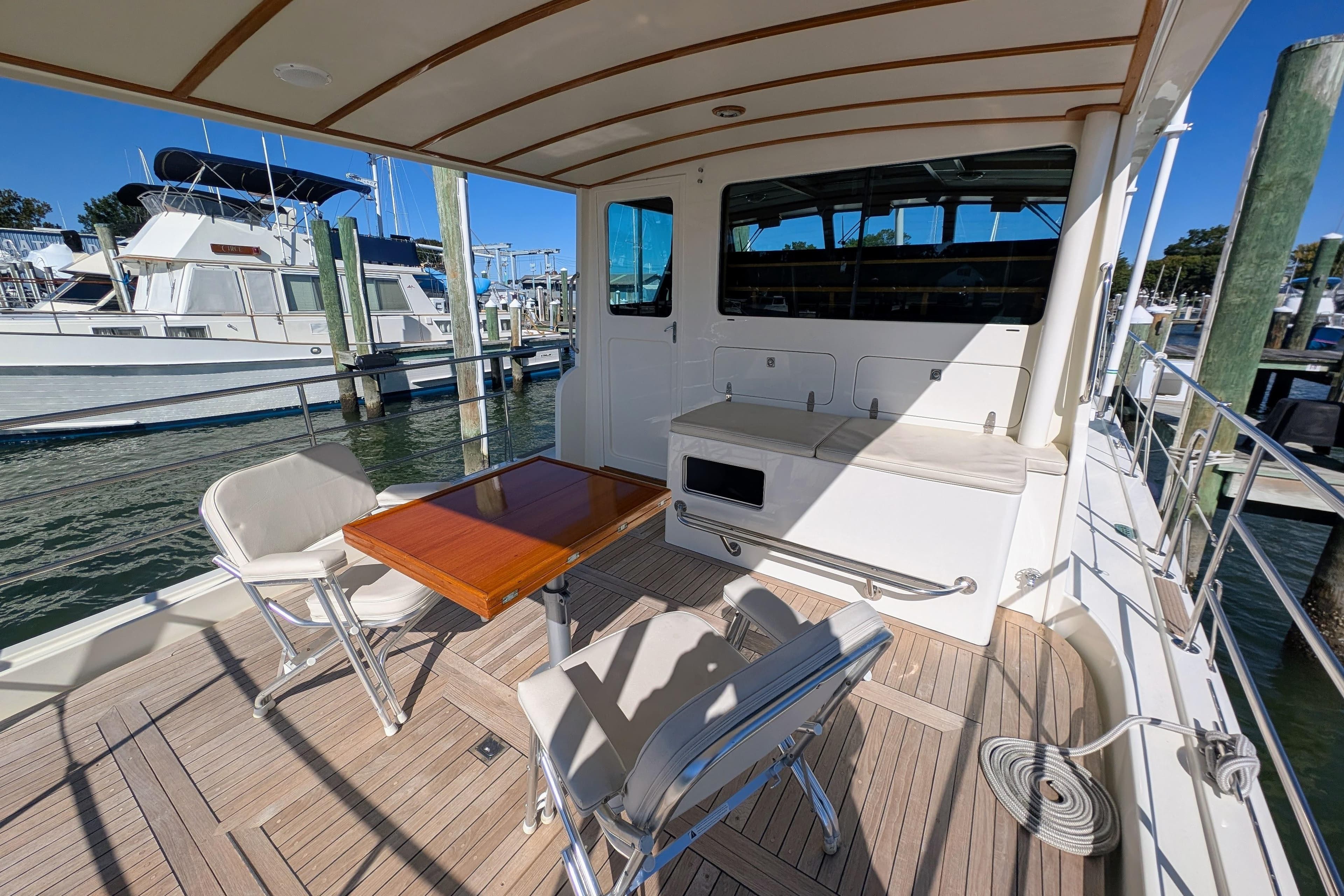 Outdoor seating area on a 2001 Dettling 51 yacht, featuring a wooden table and chairs.