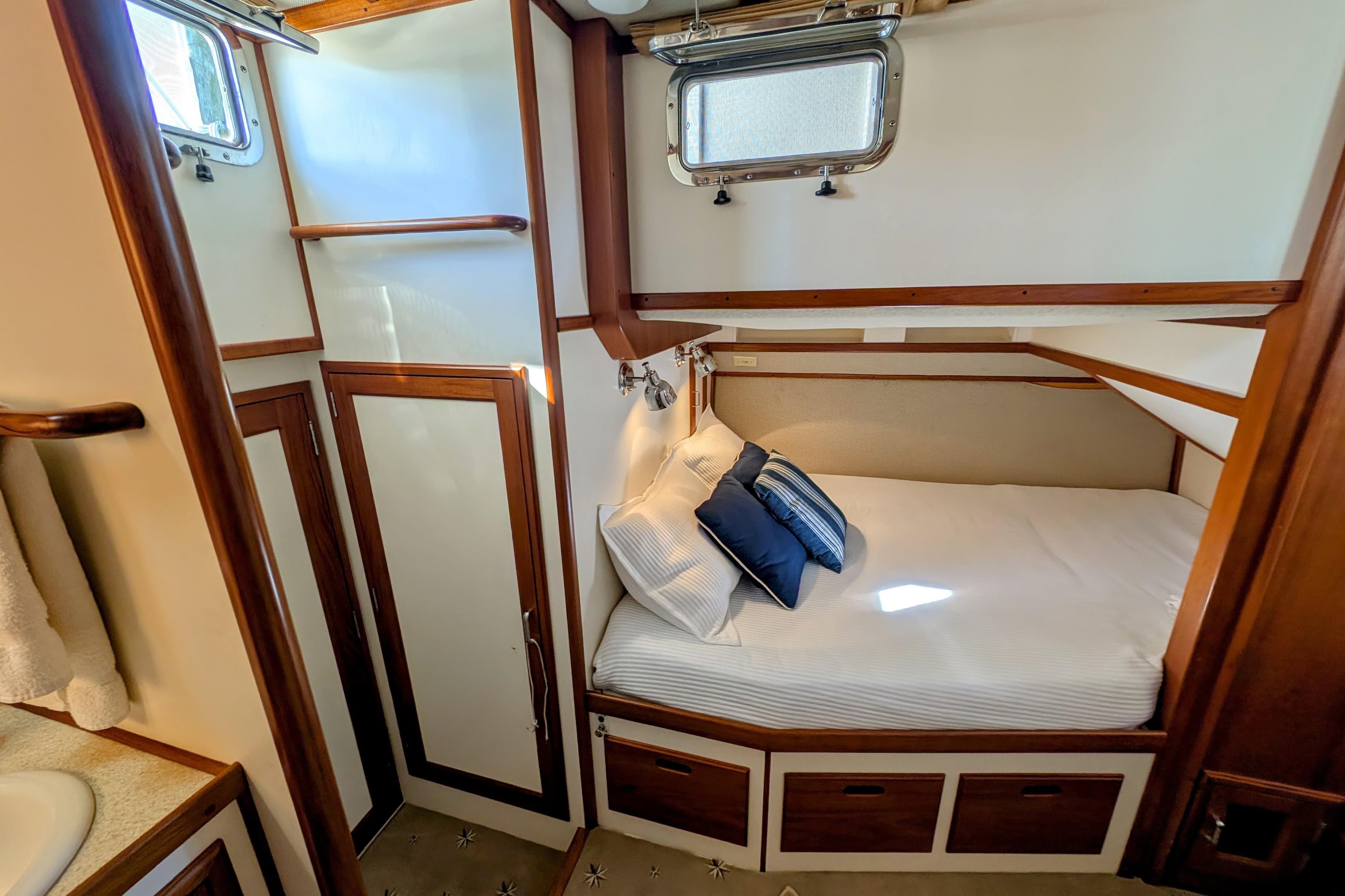 Cozy cabin interior of 2001 Dettling 51 yacht with bed and wooden accents.