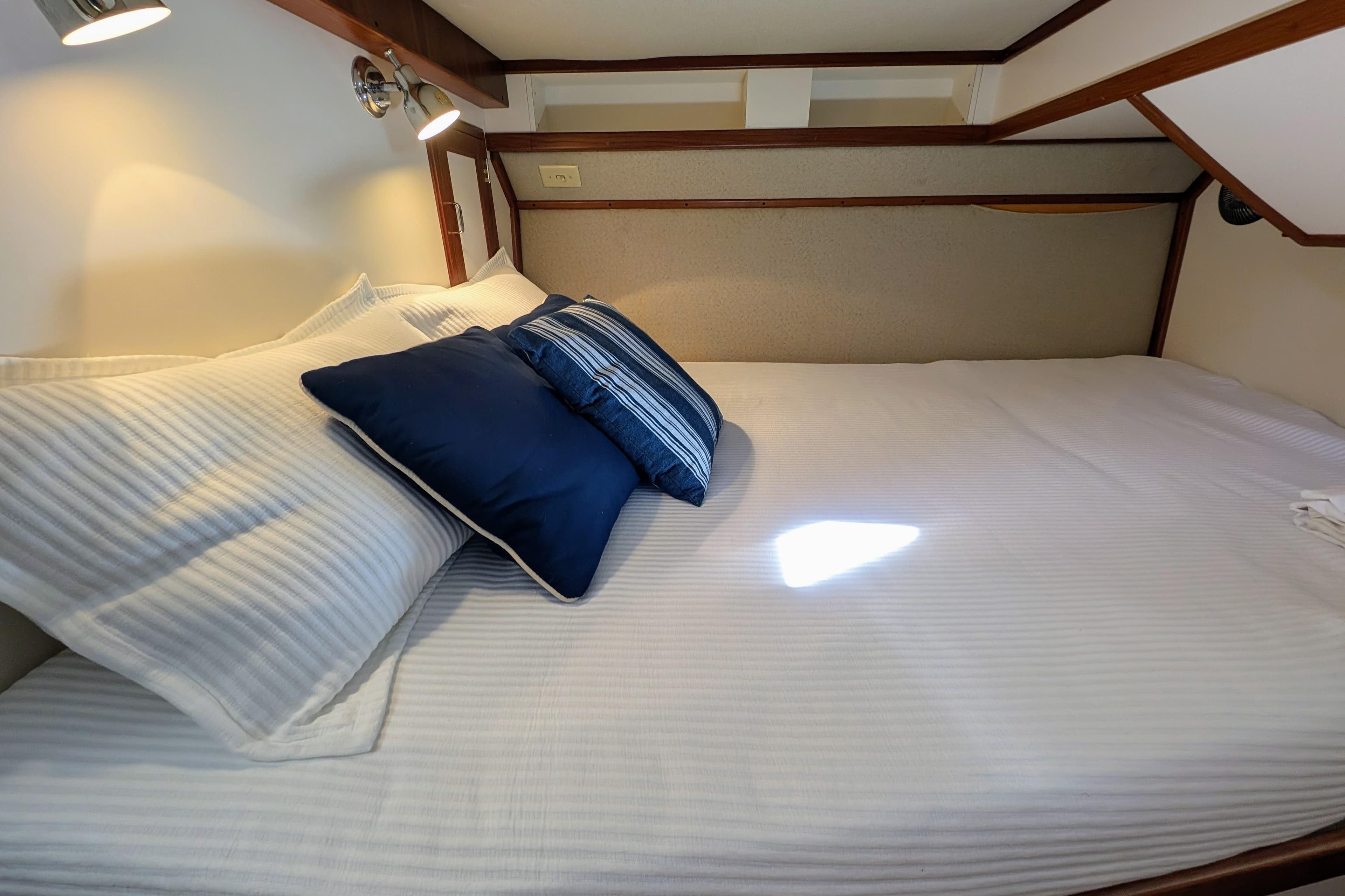 Cozy cabin bed with white and blue pillows in a 2001 Dettling 51 yacht.