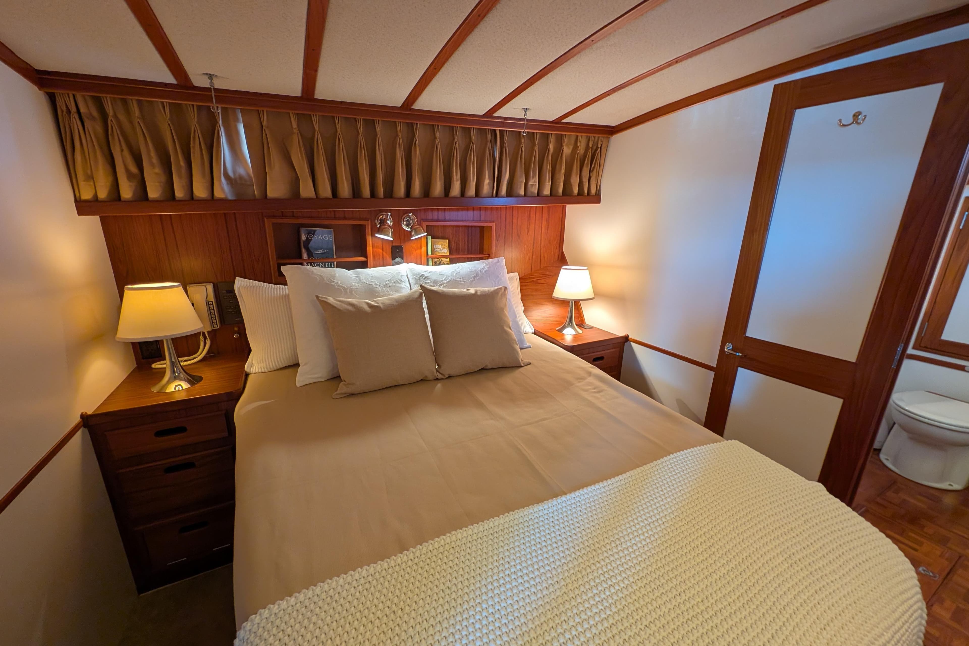 Cozy bedroom interior on 2001 Dettling 51 yacht with warm lighting and elegant wood finishes.