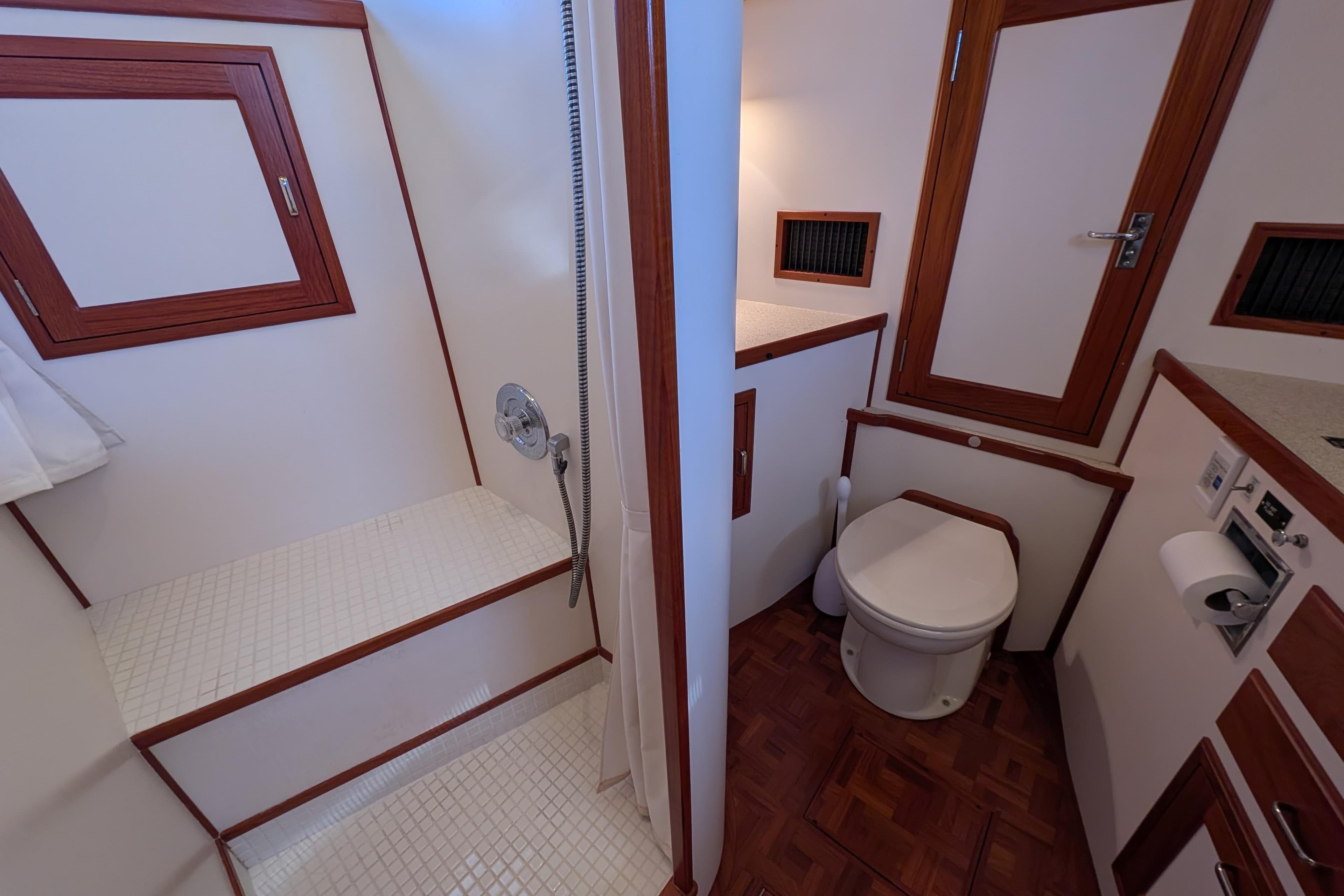 Bathroom interior of 2001 Dettling 51 yacht, featuring shower and toilet with wood accents.