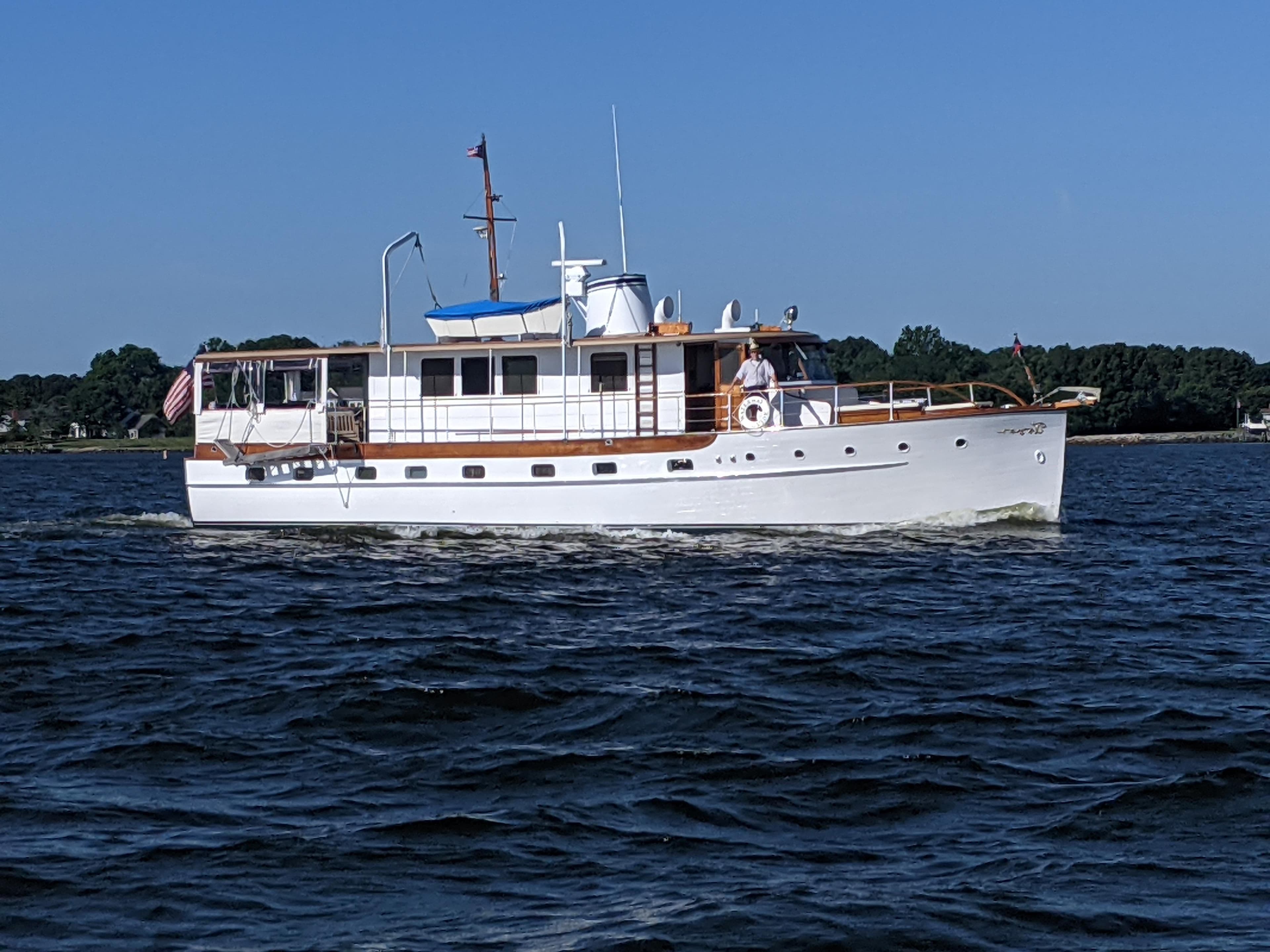 1947 Trumpy "60" Houseboat cruising on a calm lake with scenic background.