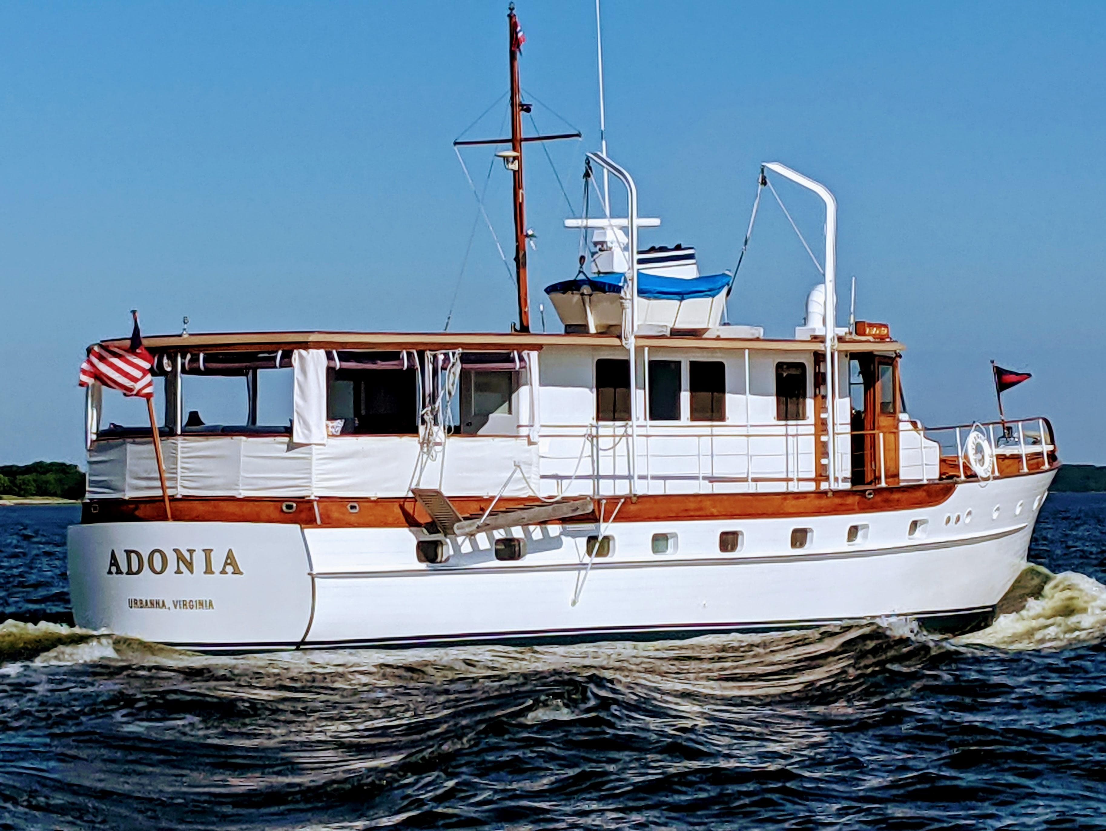 1947 Trumpy "60" Houseboat cruising on water, named Adonia, with American flag.