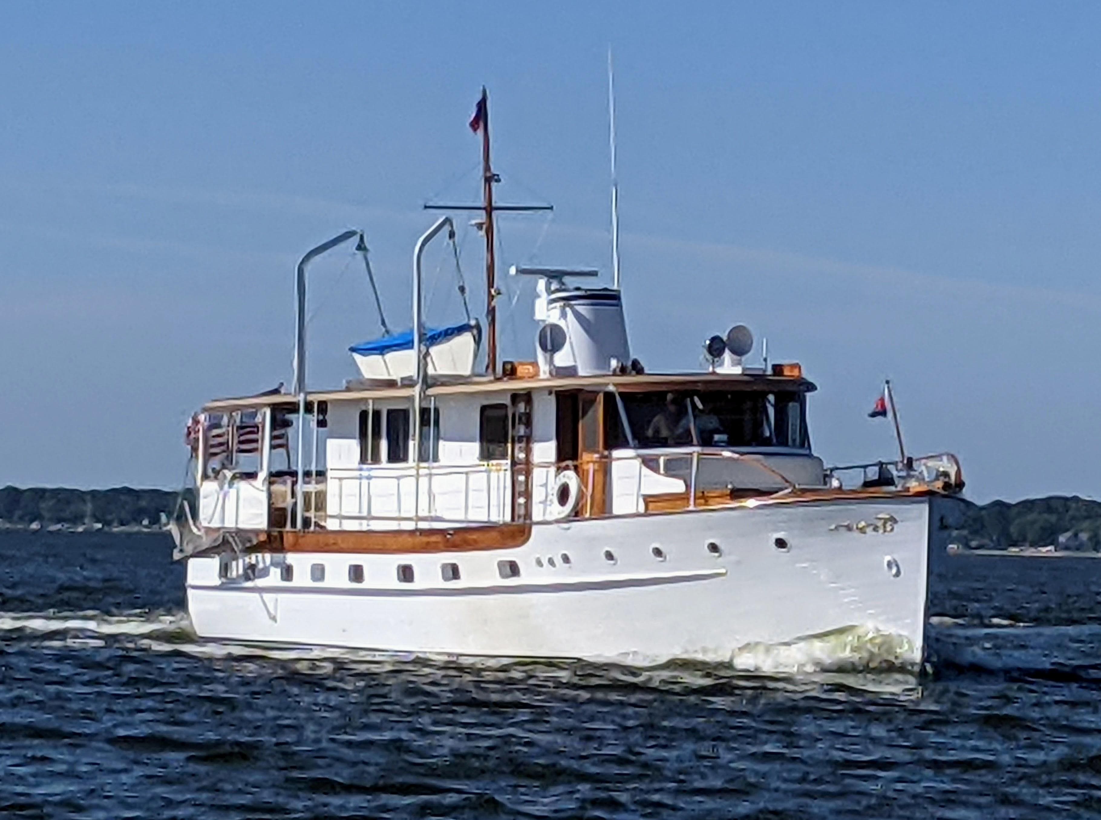 1947 Trumpy "60" Houseboat cruising on open water under clear blue skies.