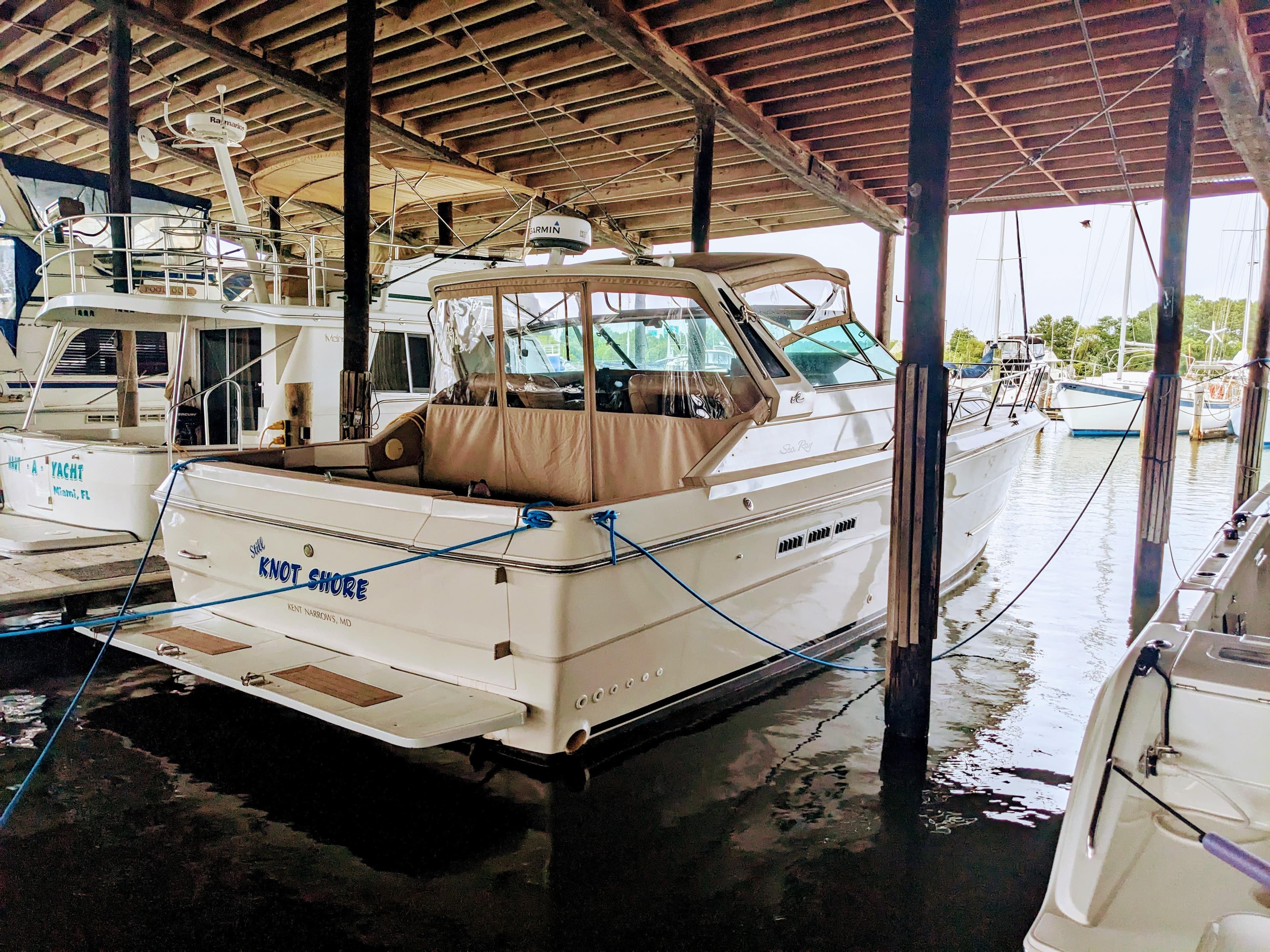 1988 Sea Ray 390 Express Cruiser docked in a marina under a wooden roof.