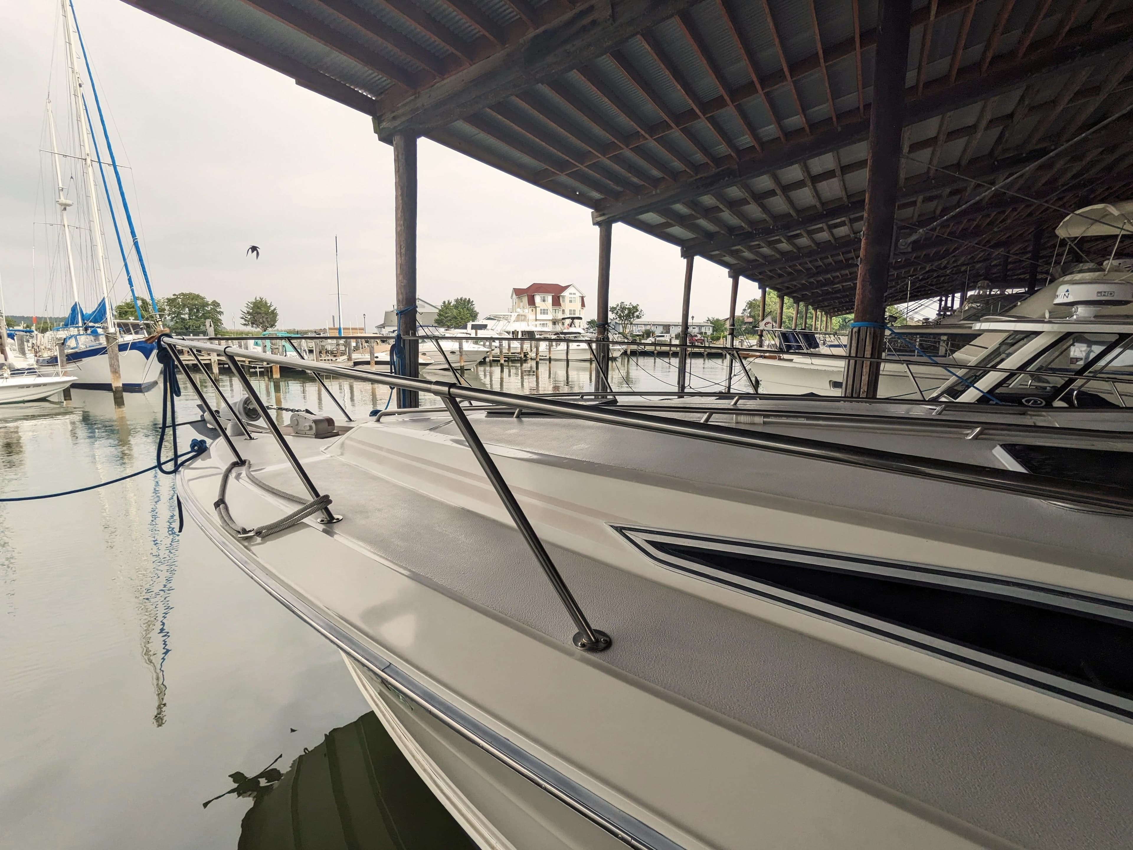1988 Sea Ray 390 Express Cruiser docked in a marina under a covered shelter.