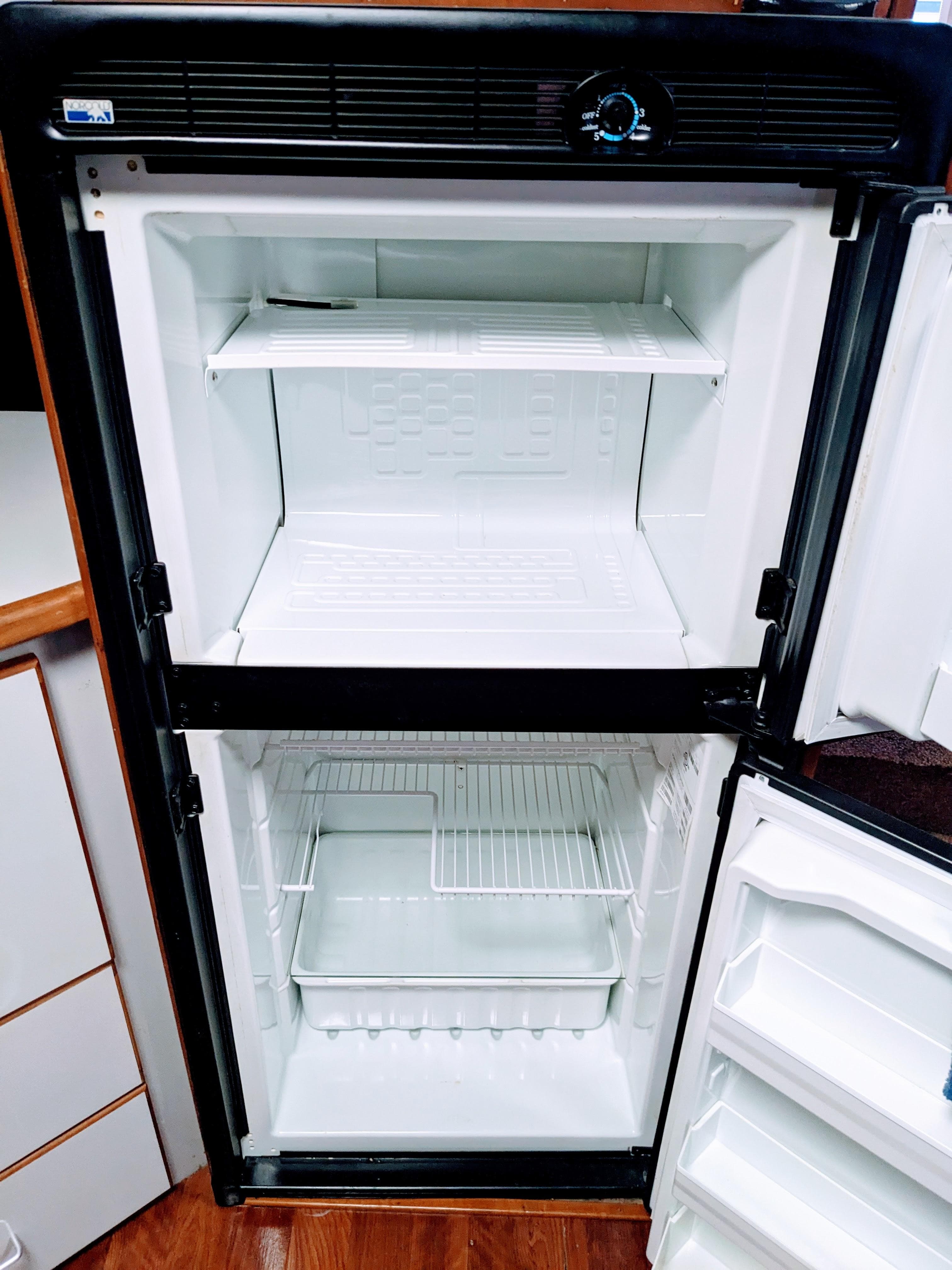 Empty refrigerator inside a 1988 Sea Ray 390 Express Cruiser boat.